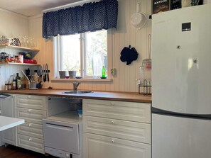 A kitchen with a window, sink, cabinets, and a refrigerator.