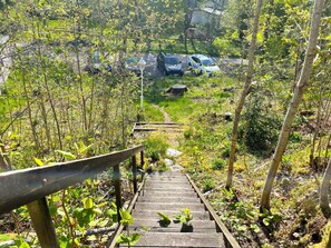 Eine Holztreppe führt zu einem Parkplatz, der von Grünflächen umgeben ist.