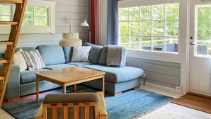 A living room with a sectional sofa, a wooden coffee table, a blue rug, and a wooden chair. - 4 Person Holiday Home in Hjarnarp (Hjarnarp)