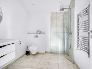 A modern bathroom with a toilet, bidet, glass shower enclosure, and a towel rack.
