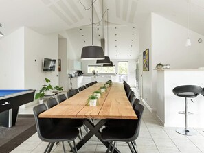 A modern dining area with a long wooden table, black chairs, and pendant lighting. - 5 Star Holiday Home in Jerup (Jerup)