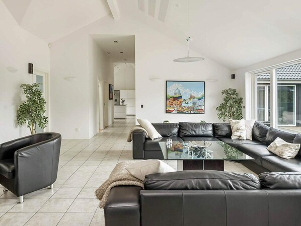 A modern living room with a sectional sofa, a glass coffee table, and a painting on the wall.