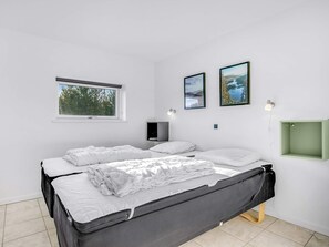 A minimalist bedroom with a bed, a window, and two framed pictures on the wall. - 5 Star Holiday Home in Jerup (Jerup)