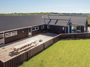 A modern building with a sloped roof, large windows, and a wooden deck. - 5 Star Holiday Home in Jerup (Jerup)
