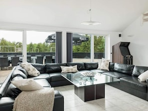 A modern living room with a sectional sofa, a glass coffee table, and a piano.