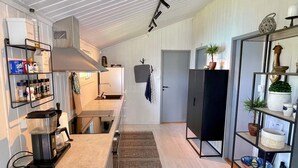 A compact kitchen with a built-in stove, a coffee machine, and a shelf with kitchen essentials. - 6 Person Holiday Home in Etne (Etne)