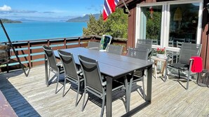 A wooden deck with a table and chairs, overlooking a body of water and mountains. - 6 Person Holiday Home in Etne (Etne)