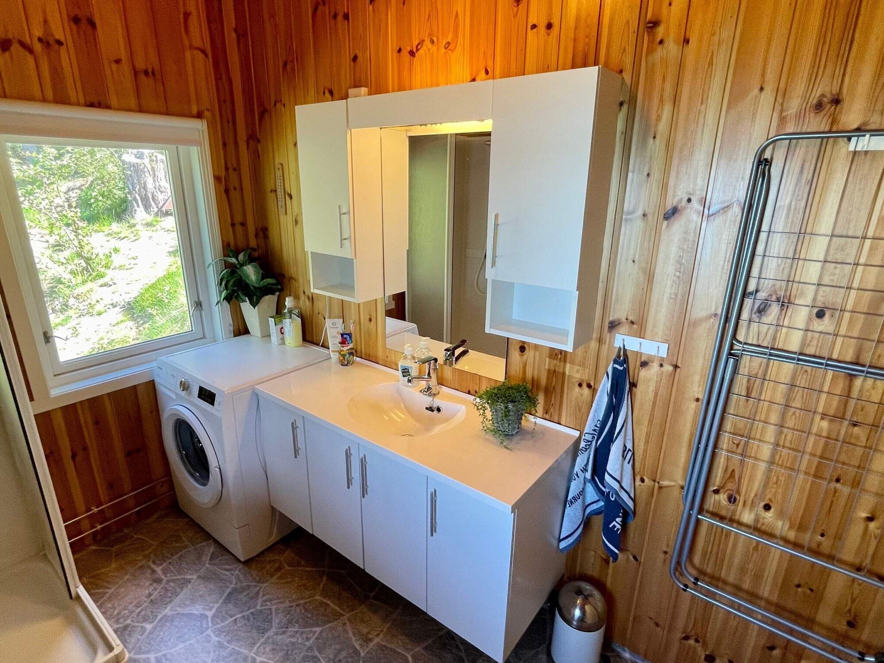 Ein kleines Badezimmer mit Waschmaschine, Waschbecken und Spiegel.