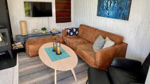 A cozy living room with a brown sofa, a coffee table, and a TV mounted on the wall. - 6 Person Holiday Home in Etne (Etne)