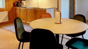 A round dining table with four chairs, a roll of paper towels, and wooden cabinets in the background. - 5 Person Holiday Home in Hagfors (Hagfors)