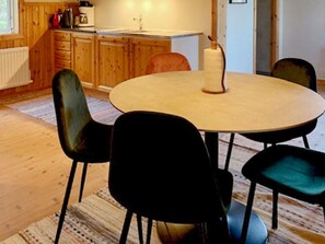 A round dining table with four chairs, a roll of paper towels, and wooden cabinets in the background. - 5 Person Holiday Home in Hagfors (Hagfors)