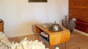 A room with a wooden floor, a small wooden table with a metal bowl, a framed picture on the wall, and a metal basket with items. - 5 Person Holiday Home in Hagfors (Hagfors)