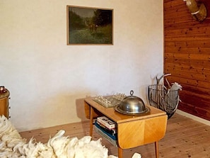 A room with a wooden floor, a small wooden table with a metal bowl, a framed picture on the wall, and a metal basket with items. - 5 Person Holiday Home in Hagfors (Hagfors)