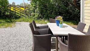 An outdoor dining area with wicker furniture and a table, surrounded by gravel. - 5 Person Holiday Home in Romakloster (Romakloster)