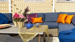 A cozy outdoor seating area with a sofa, cushions, a table with a teapot, a cup, and a book. - 5 Person Holiday Home in Romakloster (Romakloster)