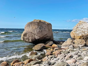 A rocky shoreline with large boulders and a clear blue sky.