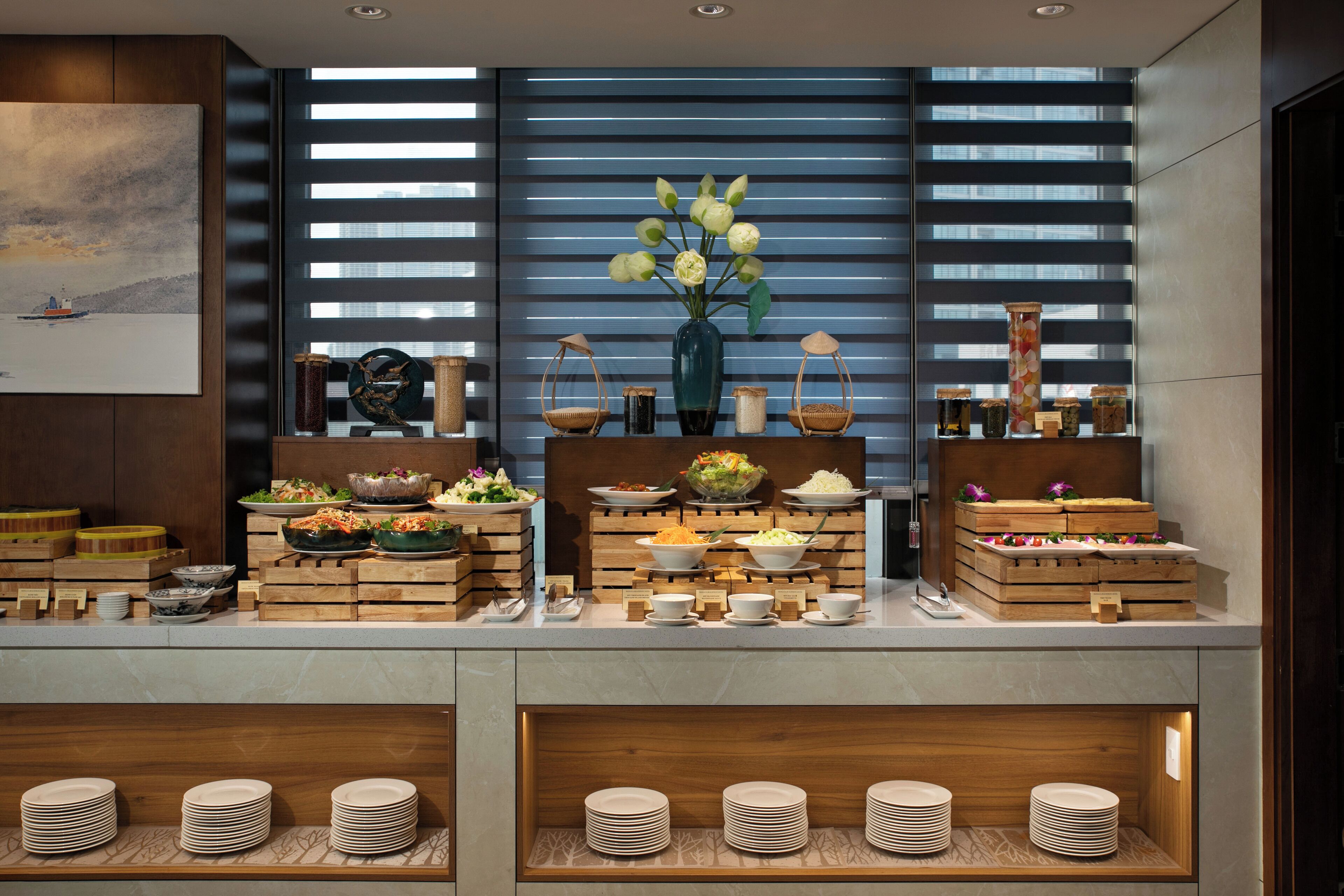 A buffet setup with various dishes and a vase of flowers.