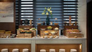 A buffet setup with various dishes and a vase of flowers.