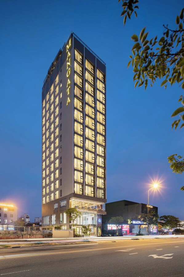 A tall hotel with illuminated windows and a sign reading "MANGATTA HOTEL".