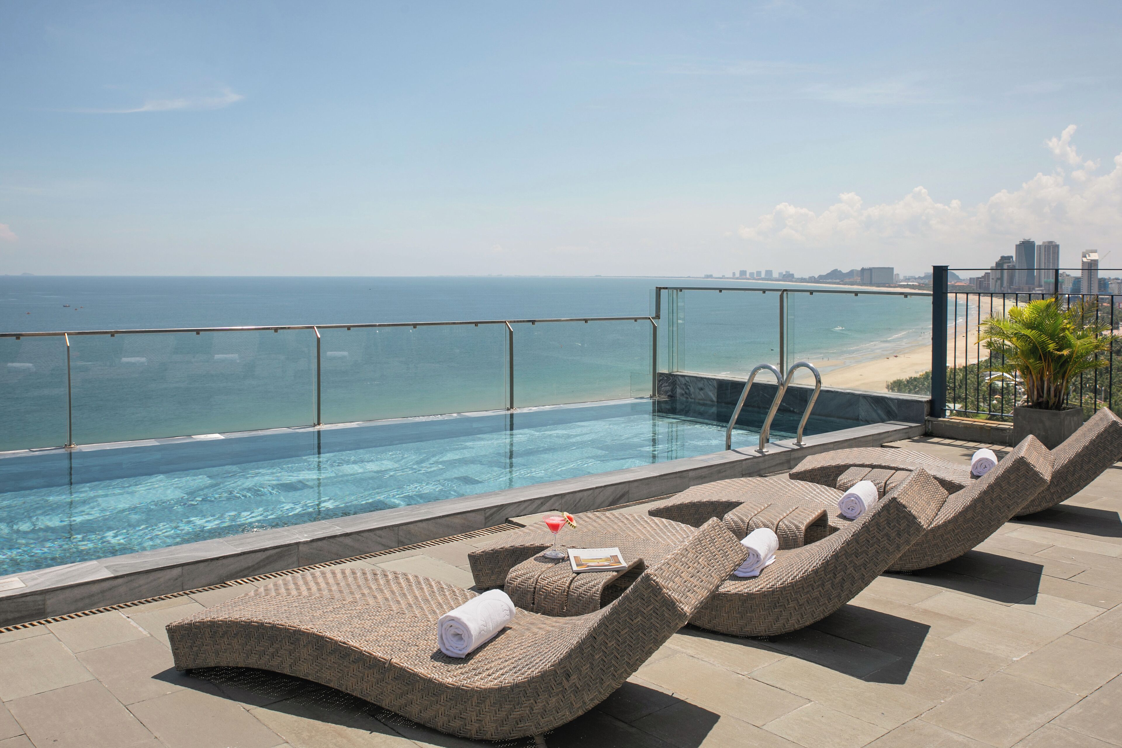 A rooftop pool area with lounge chairs and a view of the ocean.