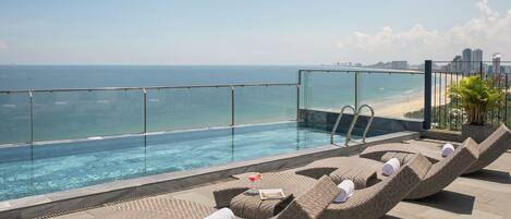 A rooftop pool area with lounge chairs and a view of the ocean.