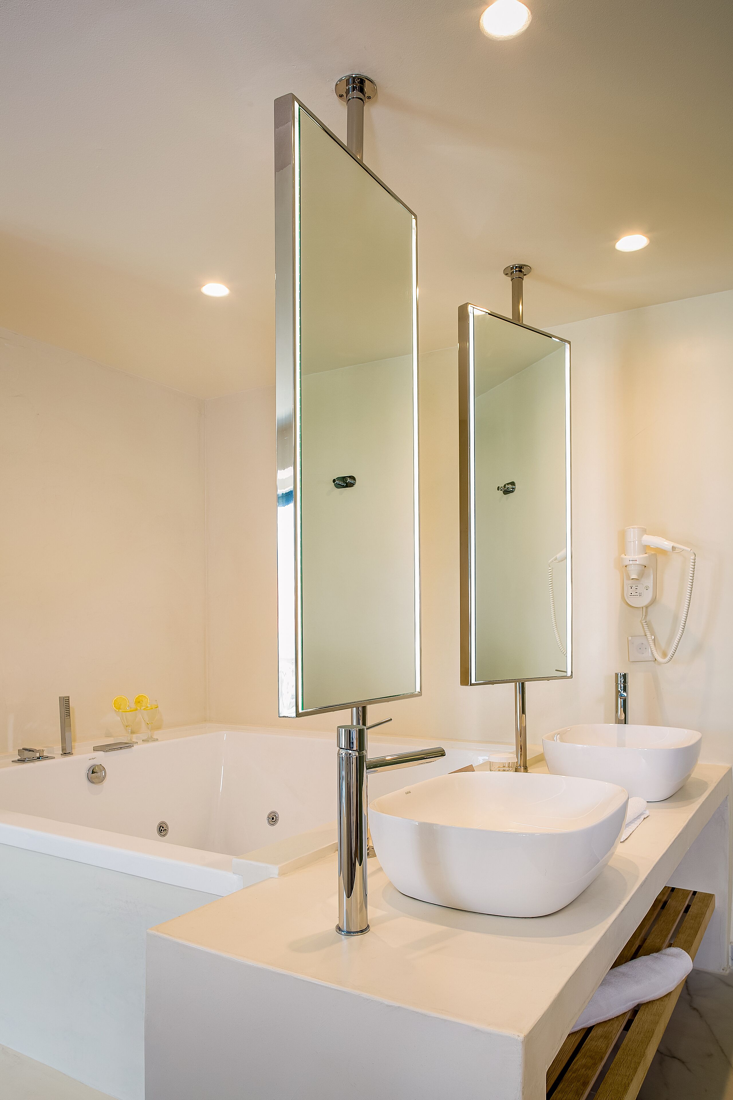 A modern bathroom with a large bathtub, two sinks, and a mirror.