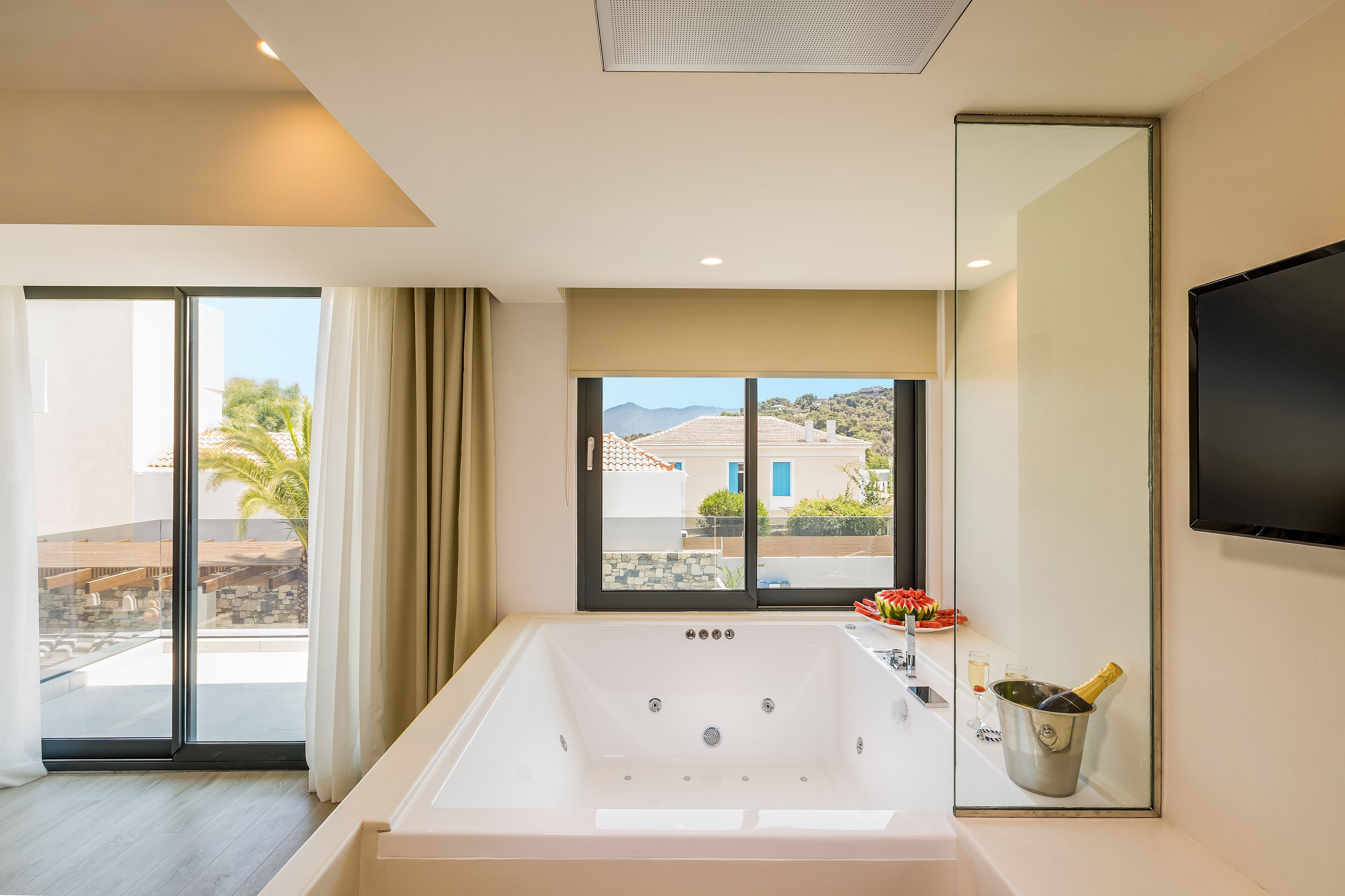Un bagno moderno con una vasca da bagno ampia, cabina doccia in vetro e vista sull'esterno.