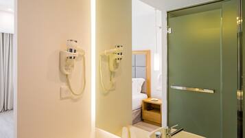 Un baño moderno con un lavamanos grande, un espejo y un secador de pelo montado en la pared.