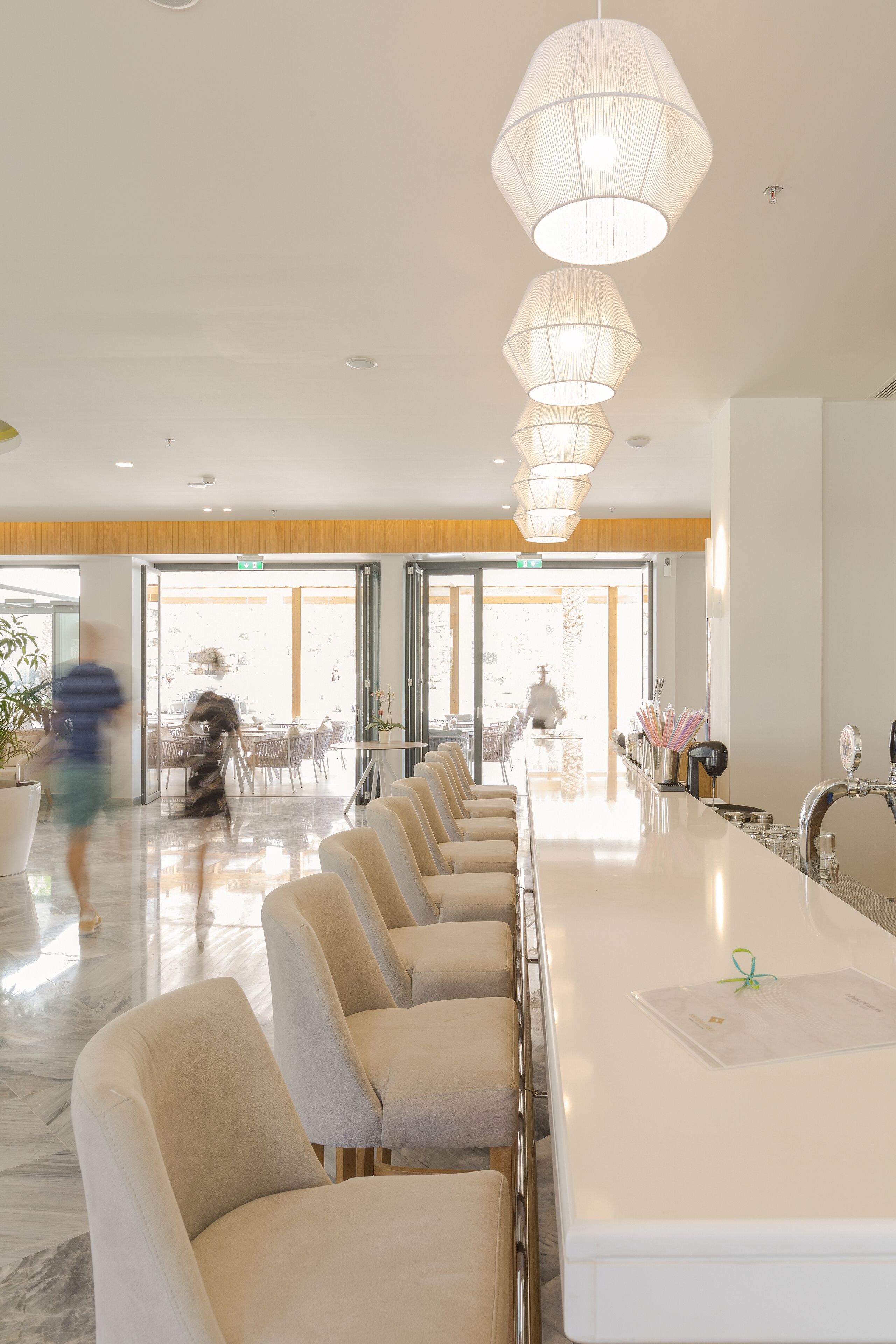 Eine moderne Hotelhalle mit einer langen Rezeption, bequemen Sitzgelegenheiten und großen Fenstern, die für natürliches Licht sorgen.