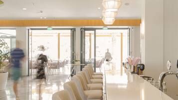 Eine moderne Hotelhalle mit einer langen Rezeption, bequemen Sitzgelegenheiten und großen Fenstern, die für natürliches Licht sorgen.