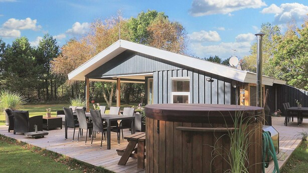 Une terrasse extérieure moderne, dotée d’une plateforme en bois, d’un jacuzzi et de mobilier d’extérieur.