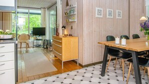 Une cuisine moderne avec des meubles en bois, une table à manger avec des chaises et un téléviseur en arrière-plan.