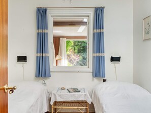 A room with two beds, a window with curtains, a small table with a lamp, and a wall-mounted speaker. - 6 Person Holiday Home in Vejby (Vejby)