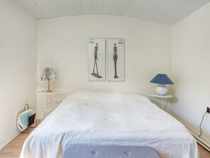 A bedroom with a bed, two wall-mounted lamps, and a small table with a lamp. - 6 Person Holiday Home in Vejby (Vejby)