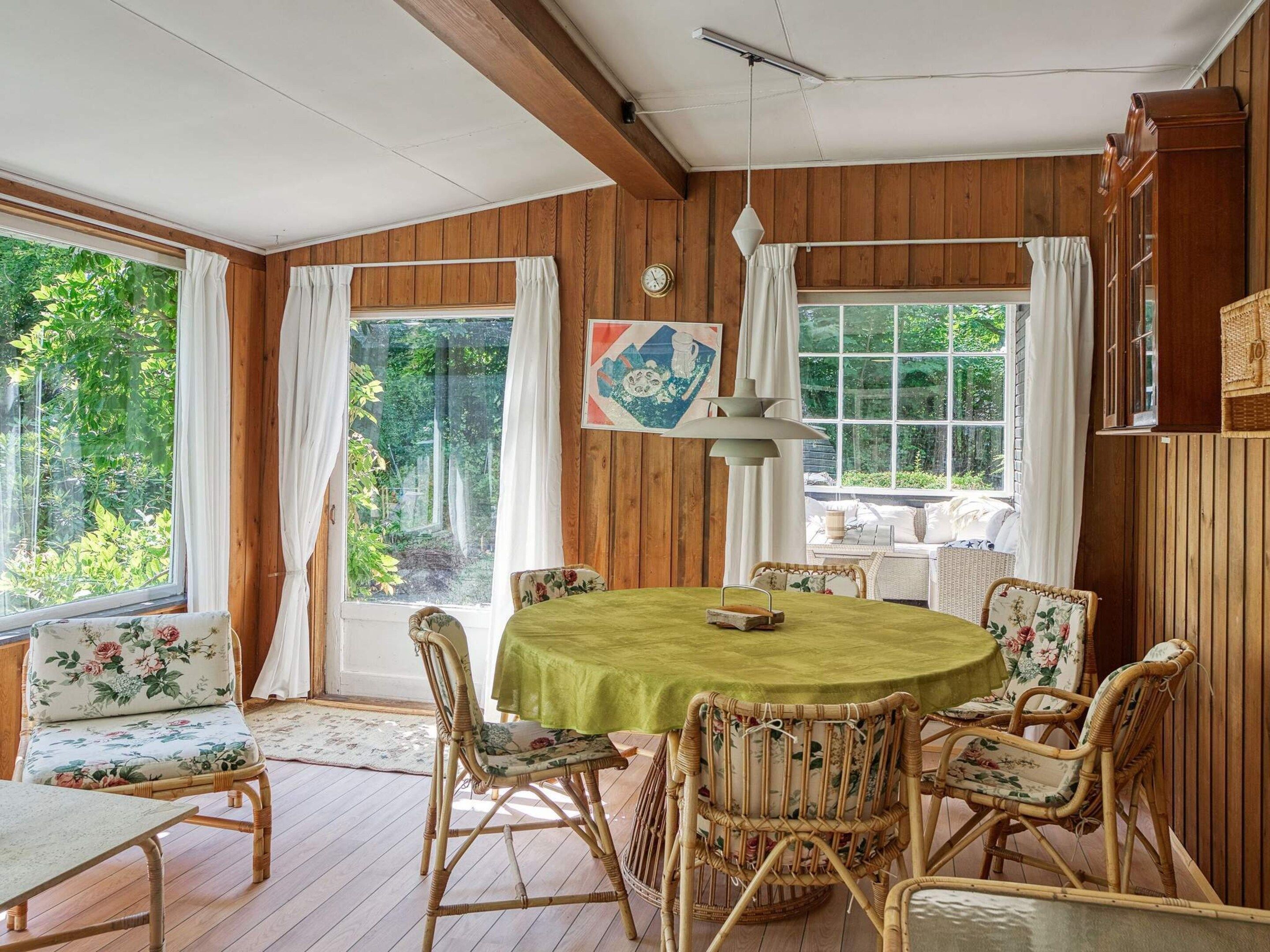 A dining area with a round table, wicker chairs, and a green tablecloth.