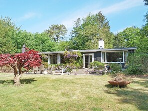 A house with a covered porch, a lawn, and a tree with red leaves. - 6 Person Holiday Home in Vejby (Vejby)