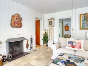 A living room with a fireplace, a clock, a couch with an American flag pillow, and a mosaic coffee table. - 6 Person Holiday Home in Vejby (Vejby)
