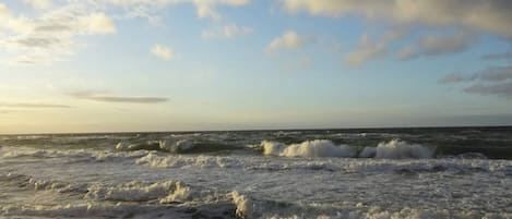 A beach with waves and a partly cloudy sky.