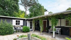A courtyard with a stone patio, a small fountain, and a white bench.