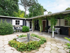 A courtyard with a stone patio, a small fountain, and a white bench. - 6 Person Holiday Home in Vejby (Vejby)