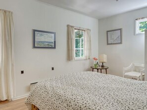 A bedroom with a bed, two windows, a chair, and a small table with a lamp. - 6 Person Holiday Home in Vejby (Vejby)