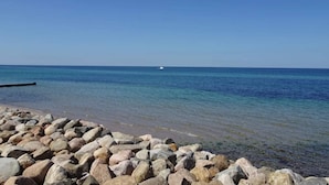 A rocky shoreline with clear blue water and a distant boat.