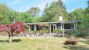 A house with a covered porch, a lawn, and a tree with red leaves.