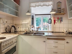 A kitchen with a window, a sink, a stove, and various kitchen utensils. - 6 Person Holiday Home in Vejby (Vejby)