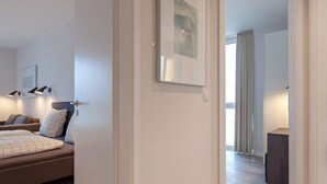 A modern bedroom with a bed, bedside lamps, and a view of a balcony.