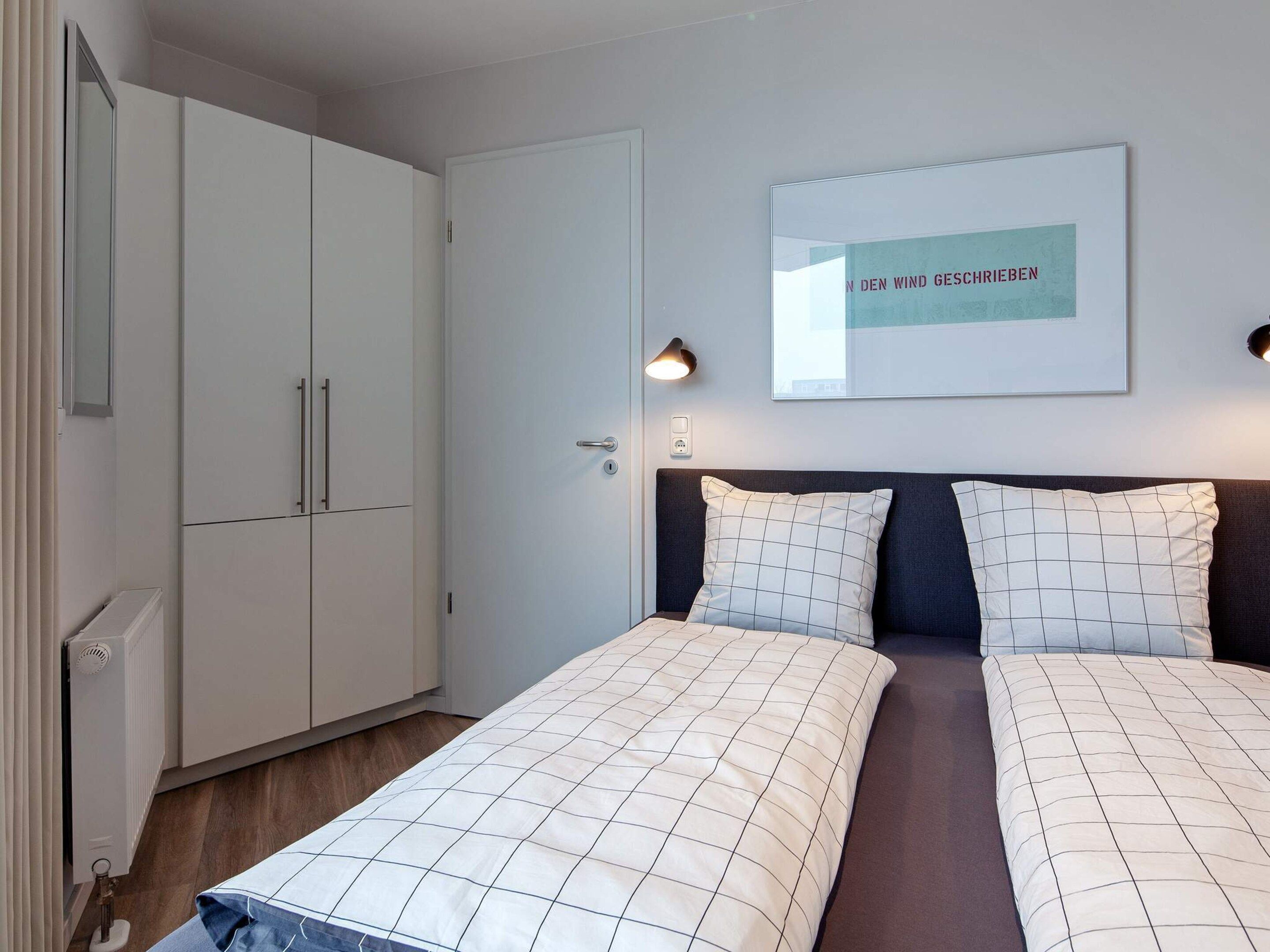 Une chambre à coucher comprenant un lit, deux tables de chevet, une armoire et un tableau encadré accroché au mur.