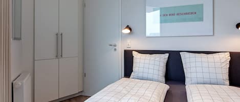 Une chambre à coucher comprenant un lit, deux tables de chevet, une armoire et un tableau encadré accroché au mur.