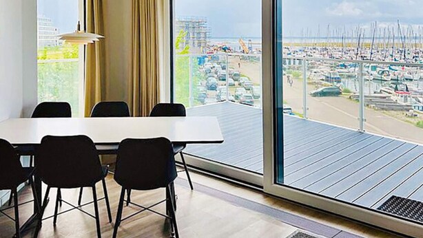 A modern hotel room with a large window offering a view of a marina and cityscape.