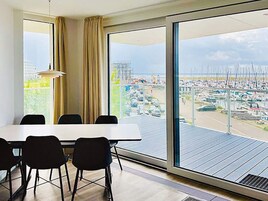 Habitación de hotel moderna con un amplio ventanal que ofrece vistas a un puerto deportivo y al paisaje urbano.