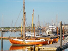 Un puerto deportivo con varias embarcaciones amarradas, pilotes de madera y un cielo despejado.